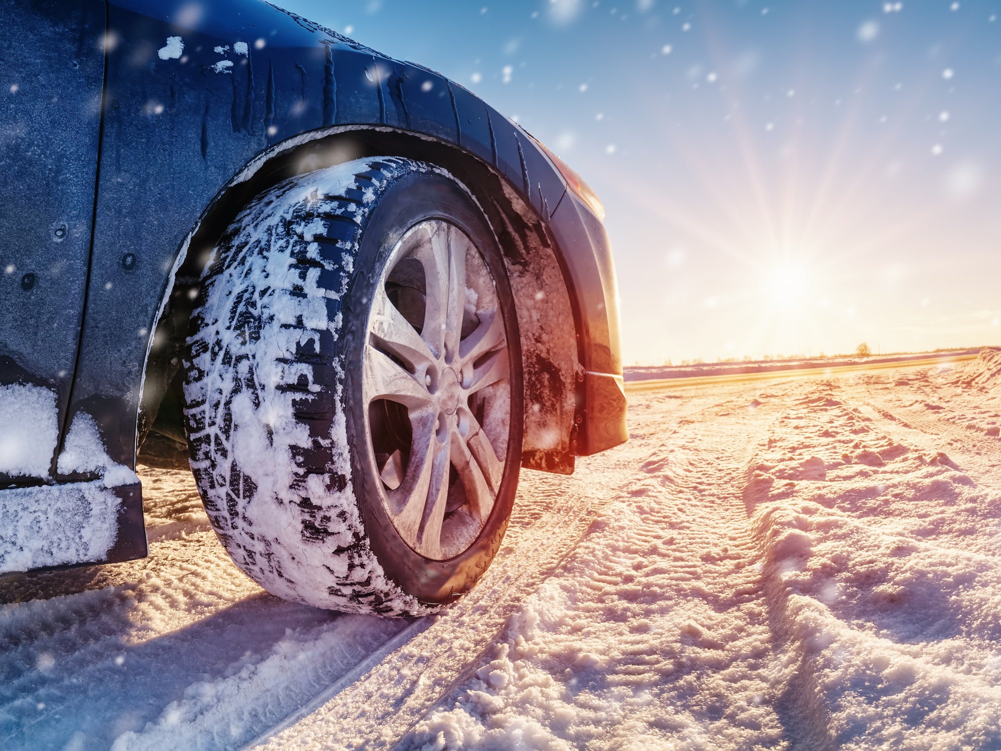 Auto steht im Sonnenlicht auf einer Schneedecke.