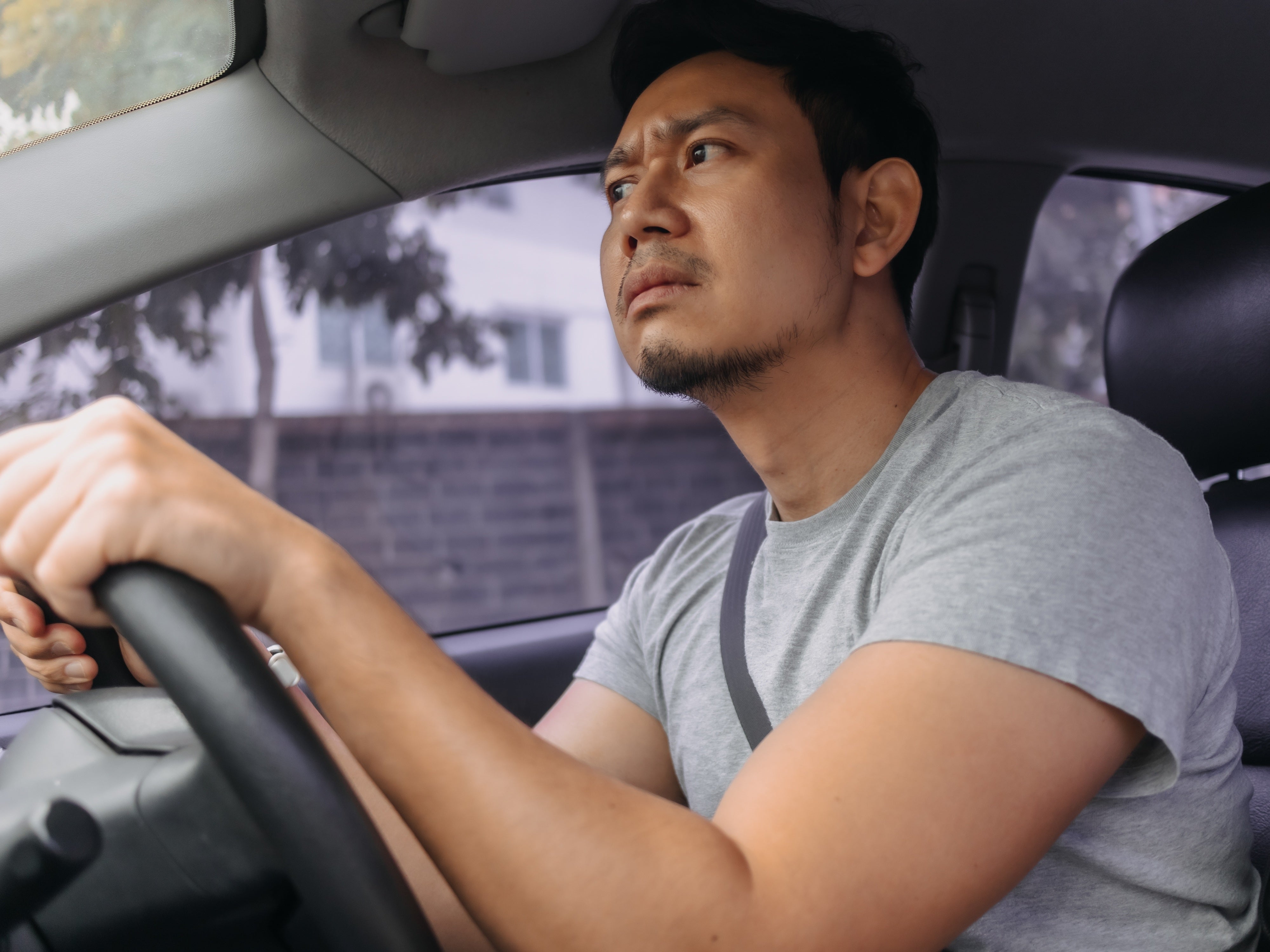 Mann sitzt im Auto am Steuer