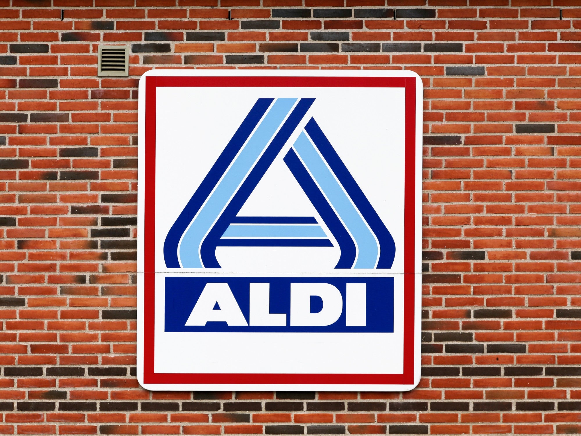 Aldi-Logo auf einer Backsteinmauer.