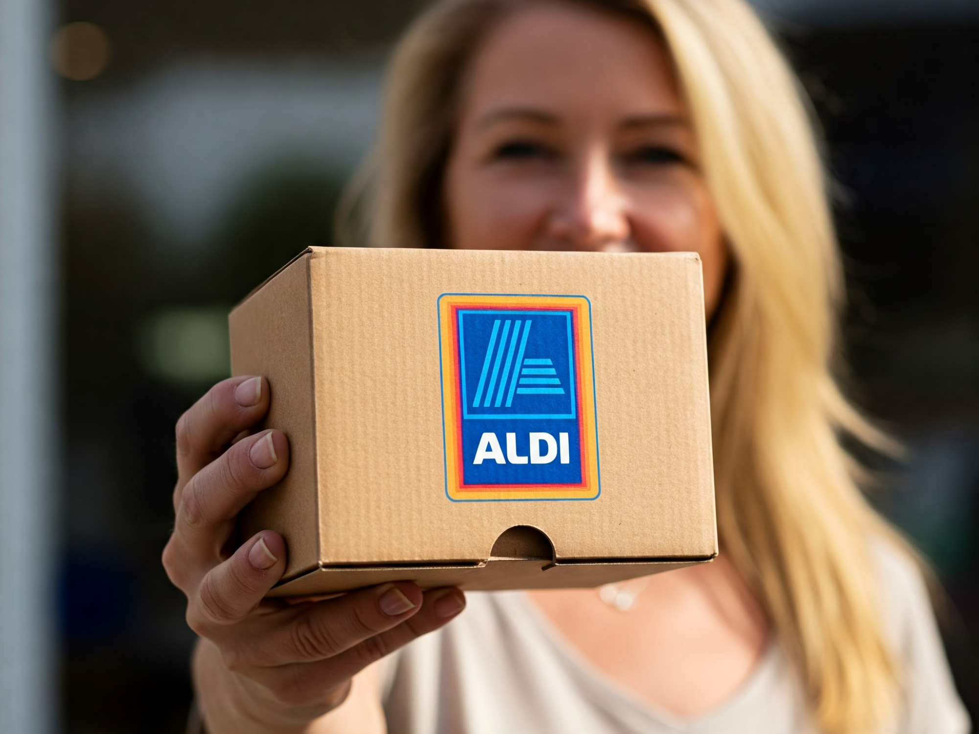 Aldi-Logo auf einem Paket, welches von einer Frau gehalten wird