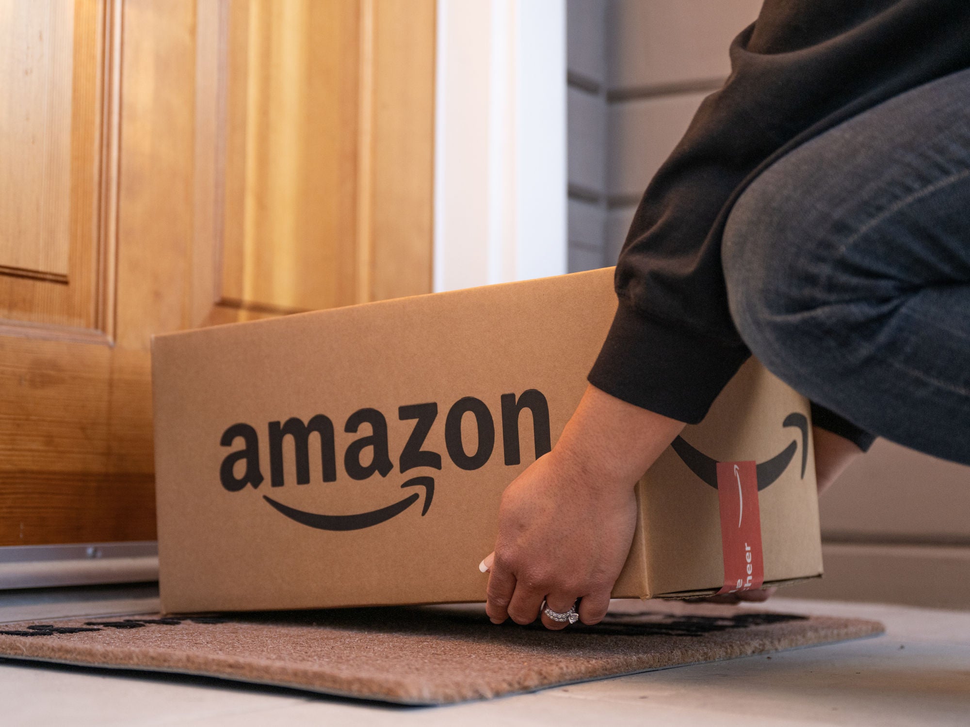 Zusteller stellt ein Amazon-Paket vor einer Haustür ab.