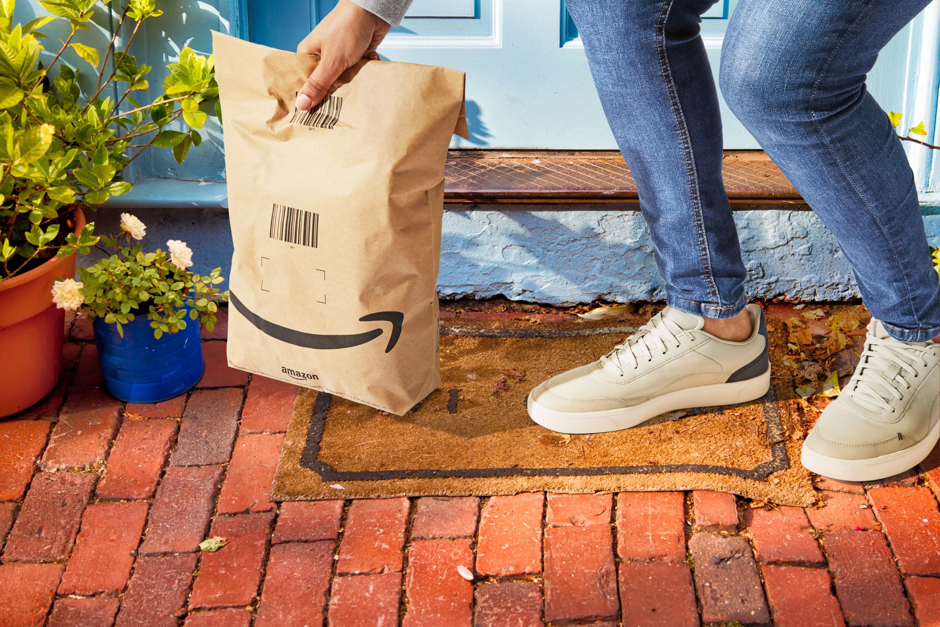 Ein Kunde hebt eine Amazon-Lieferung auf, die vor seiner Tür steht