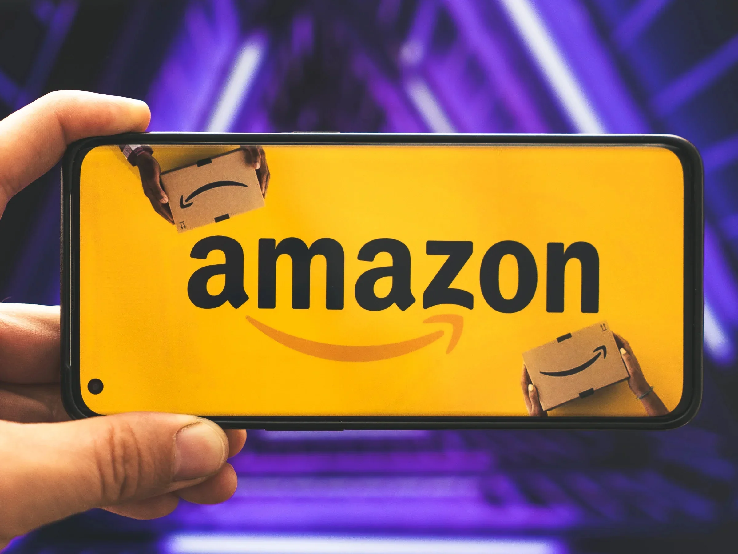 Ein Smartphone mit Amazon-Logo liegt in einer Hand