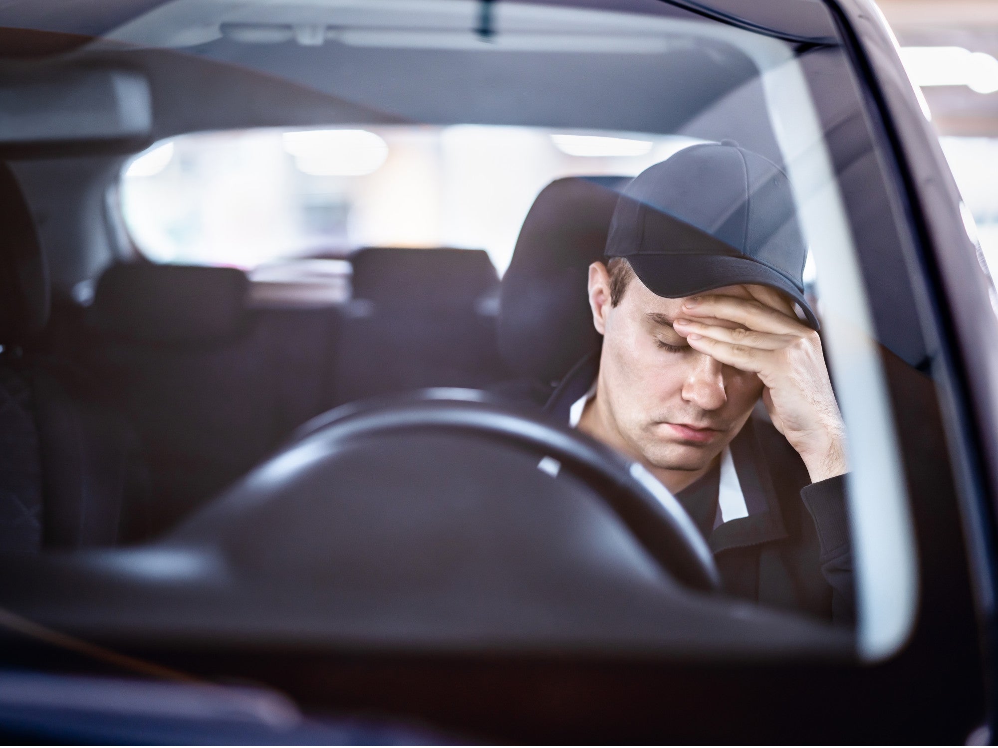 Autofahrer mit Kopfschmerzen hinter einem Lenkrad.