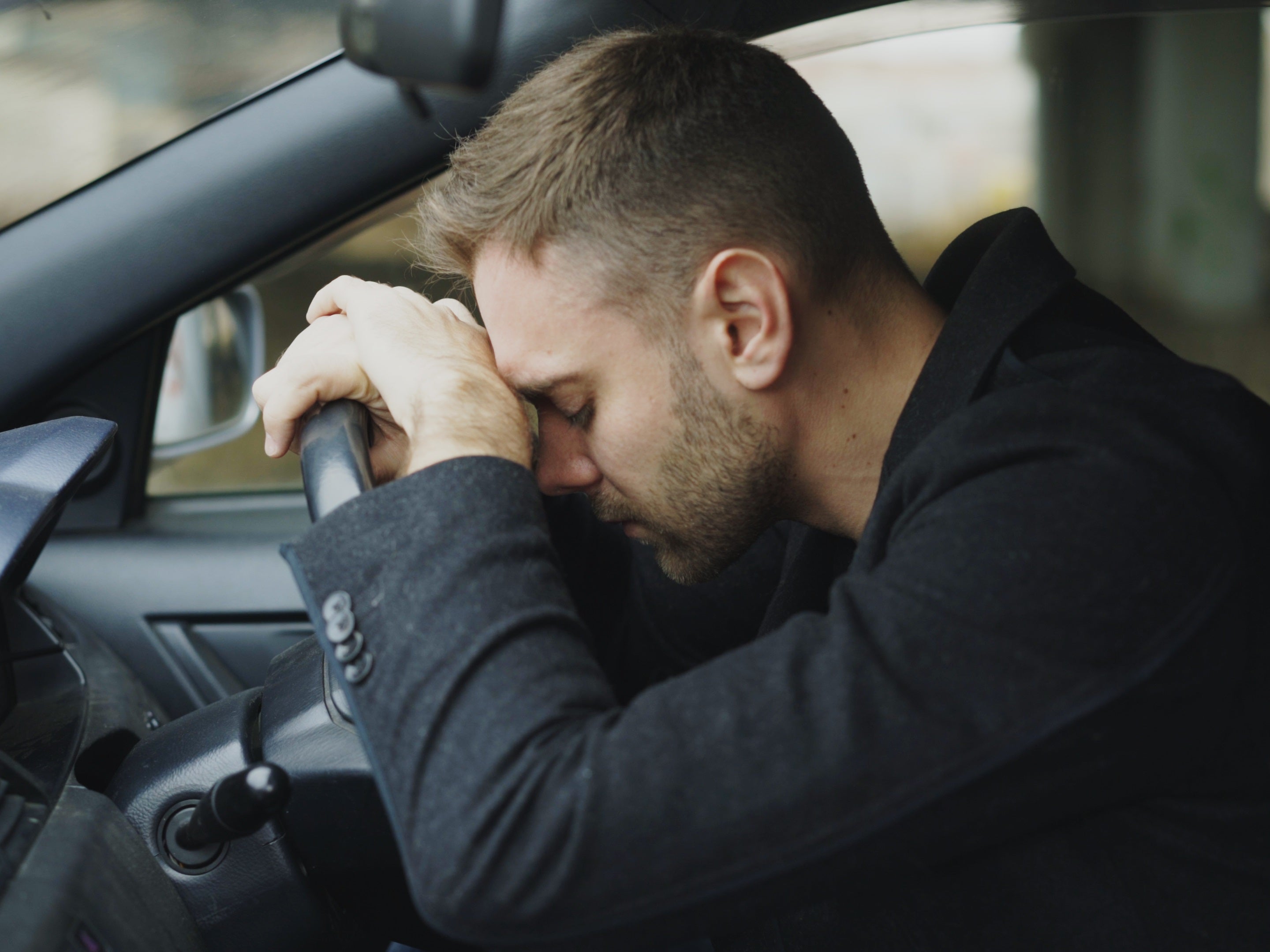 Trauriger Autofahrer lehnt am Lenkrad