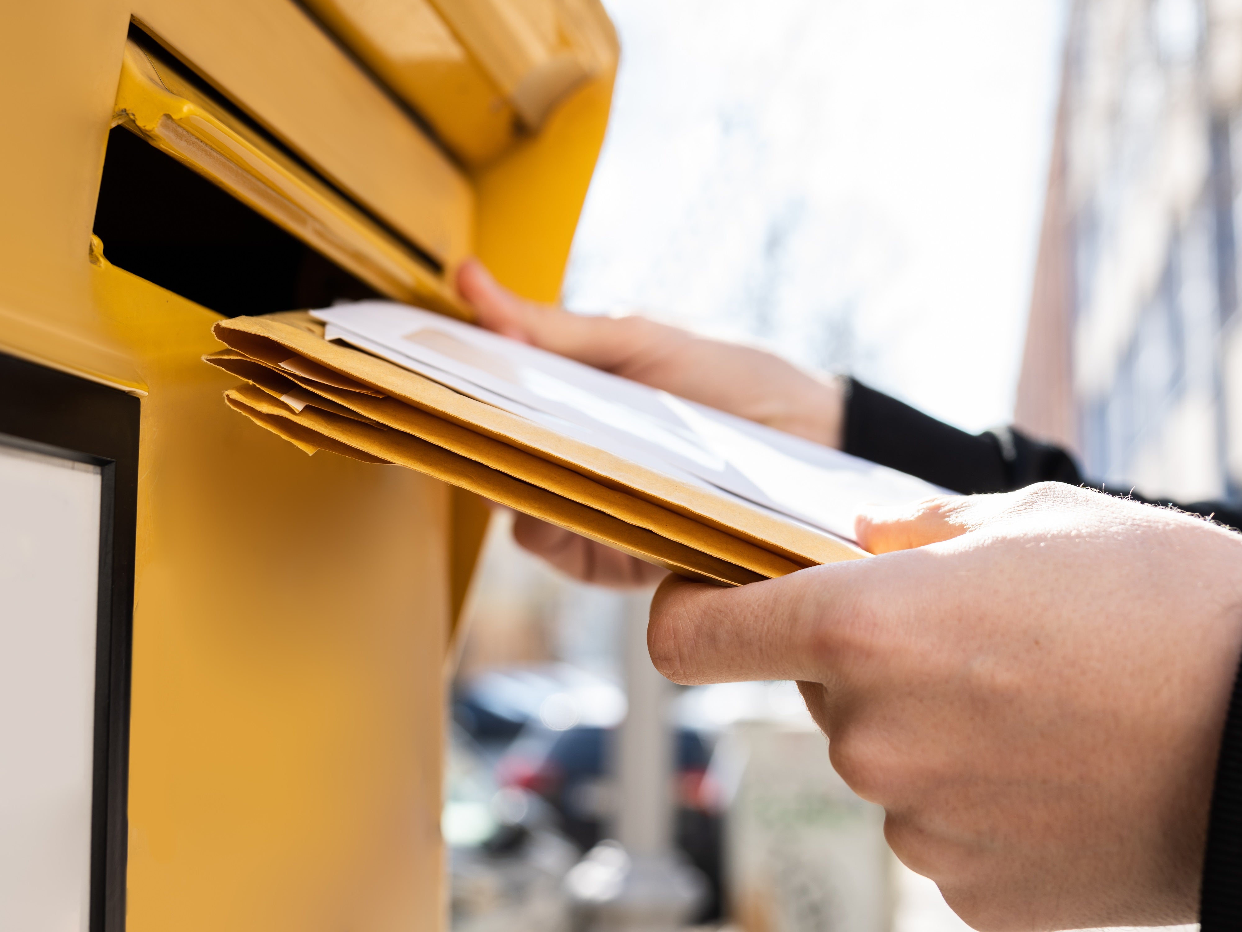 Mann wirft Briefe in einen Briefkasten