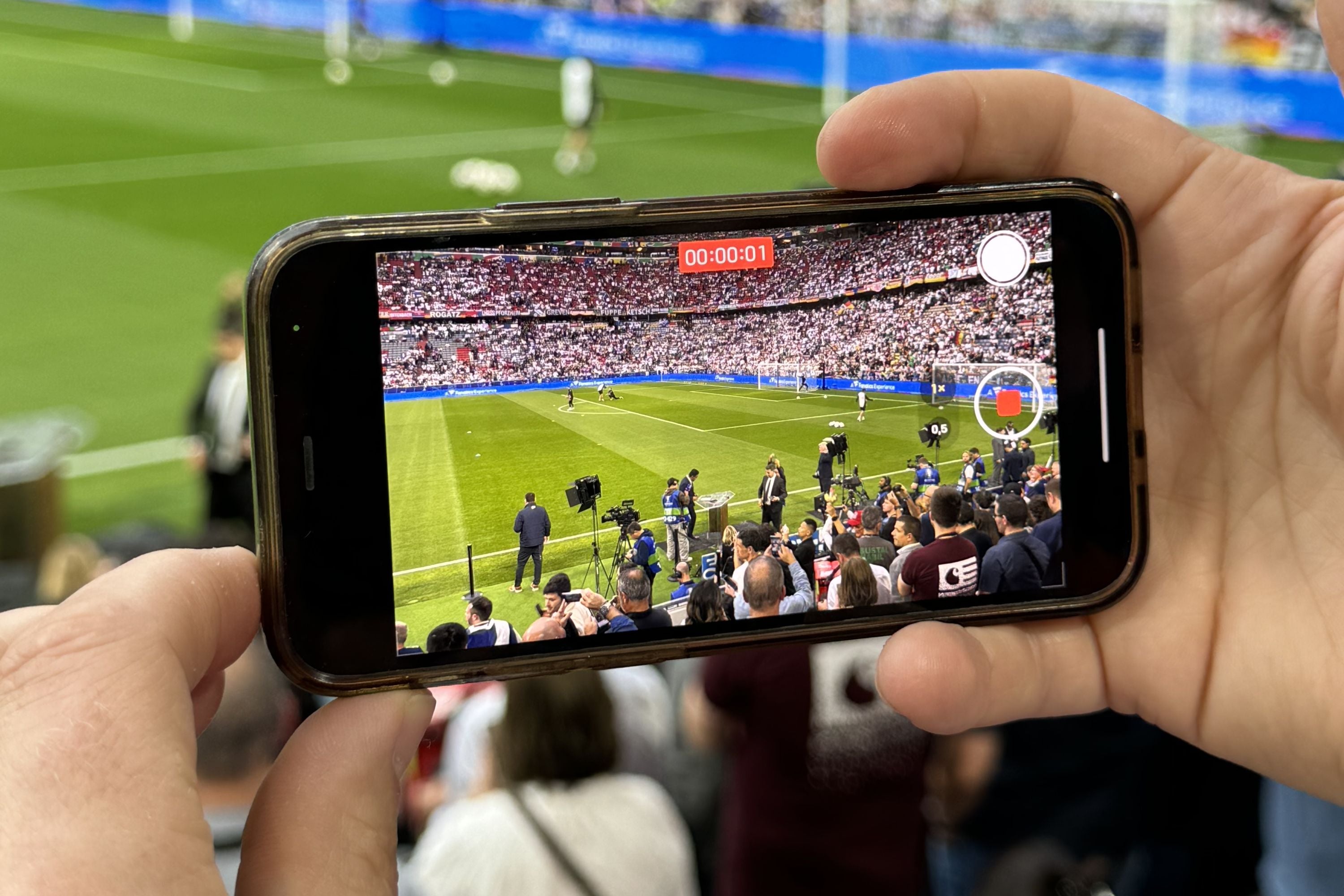 Ein Smartphone filmt im Stadion ein Fußballspiel