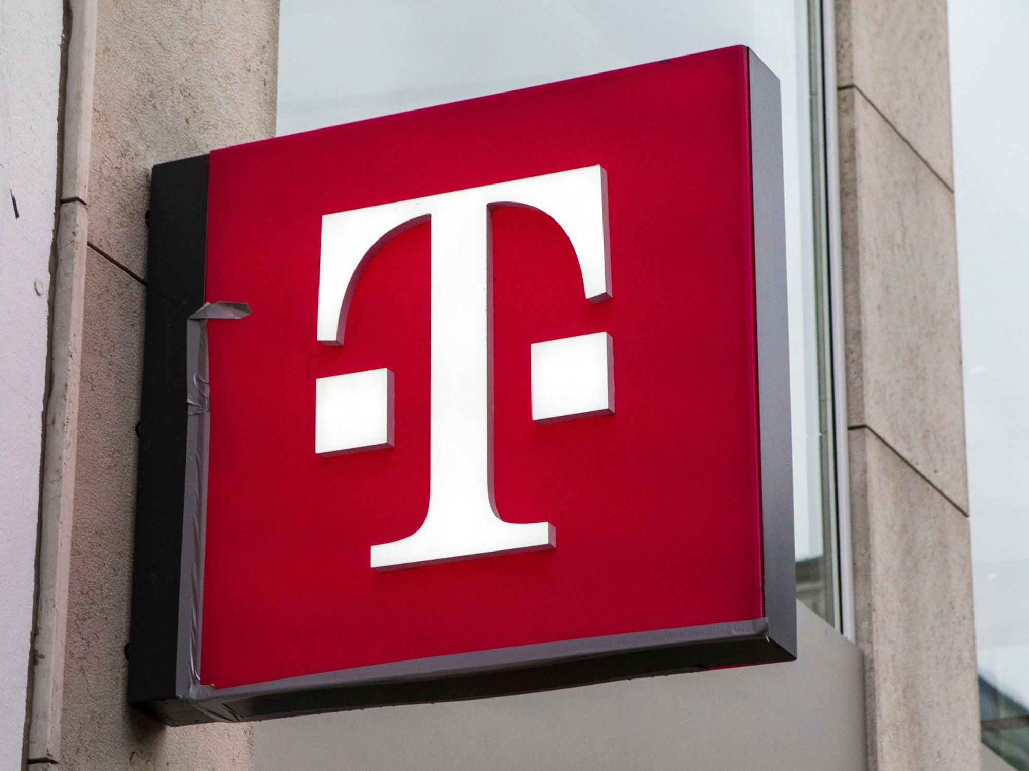 Logo der Deutschen Telekom in einer Innenstadt an einem Gebäude.