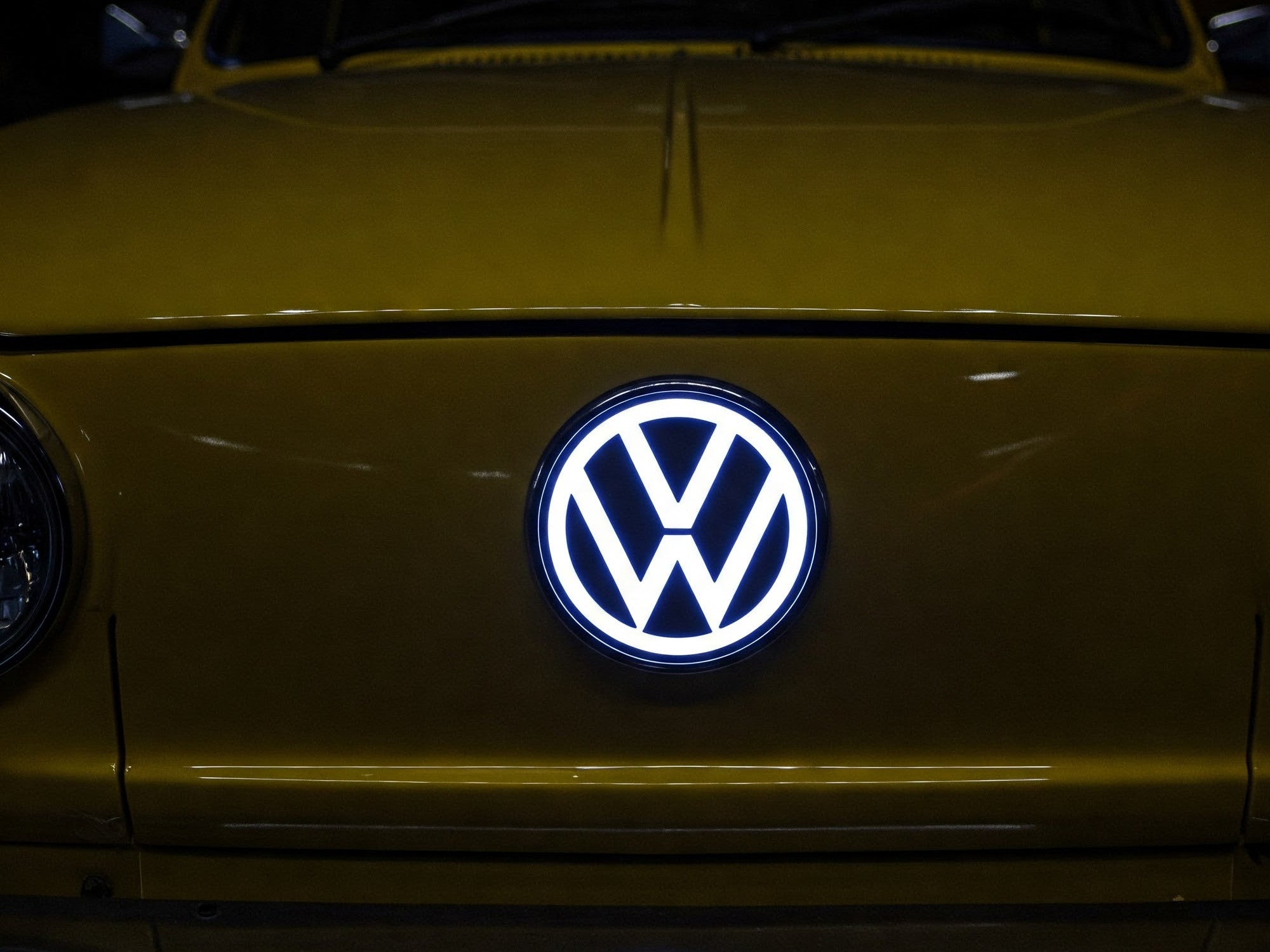 Leuchtendes Volkswagen-Logo an einem Auto.