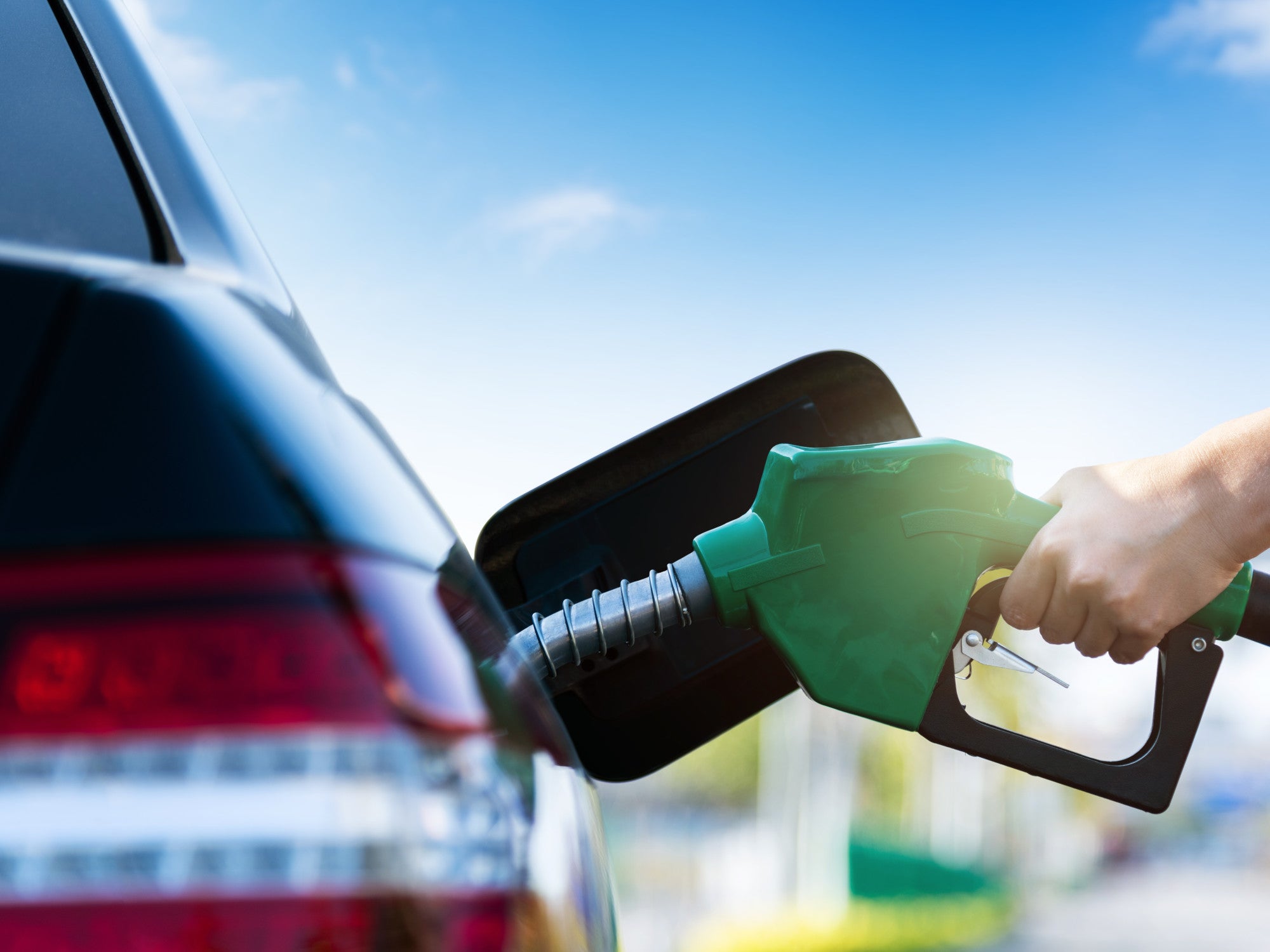 Frau tankt ein Auto an einer Tankstelle.