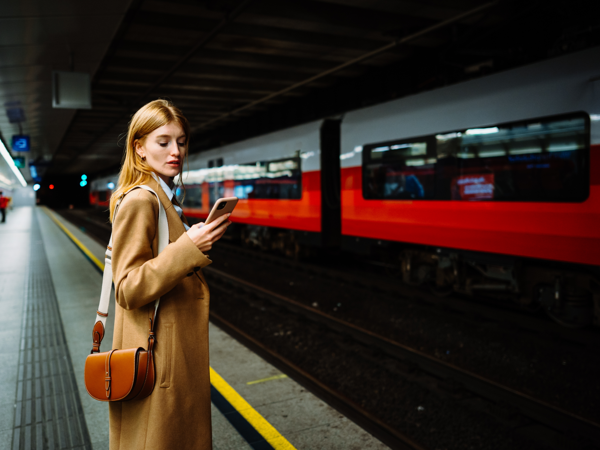 Frau am Bahnhof mit Smartphone