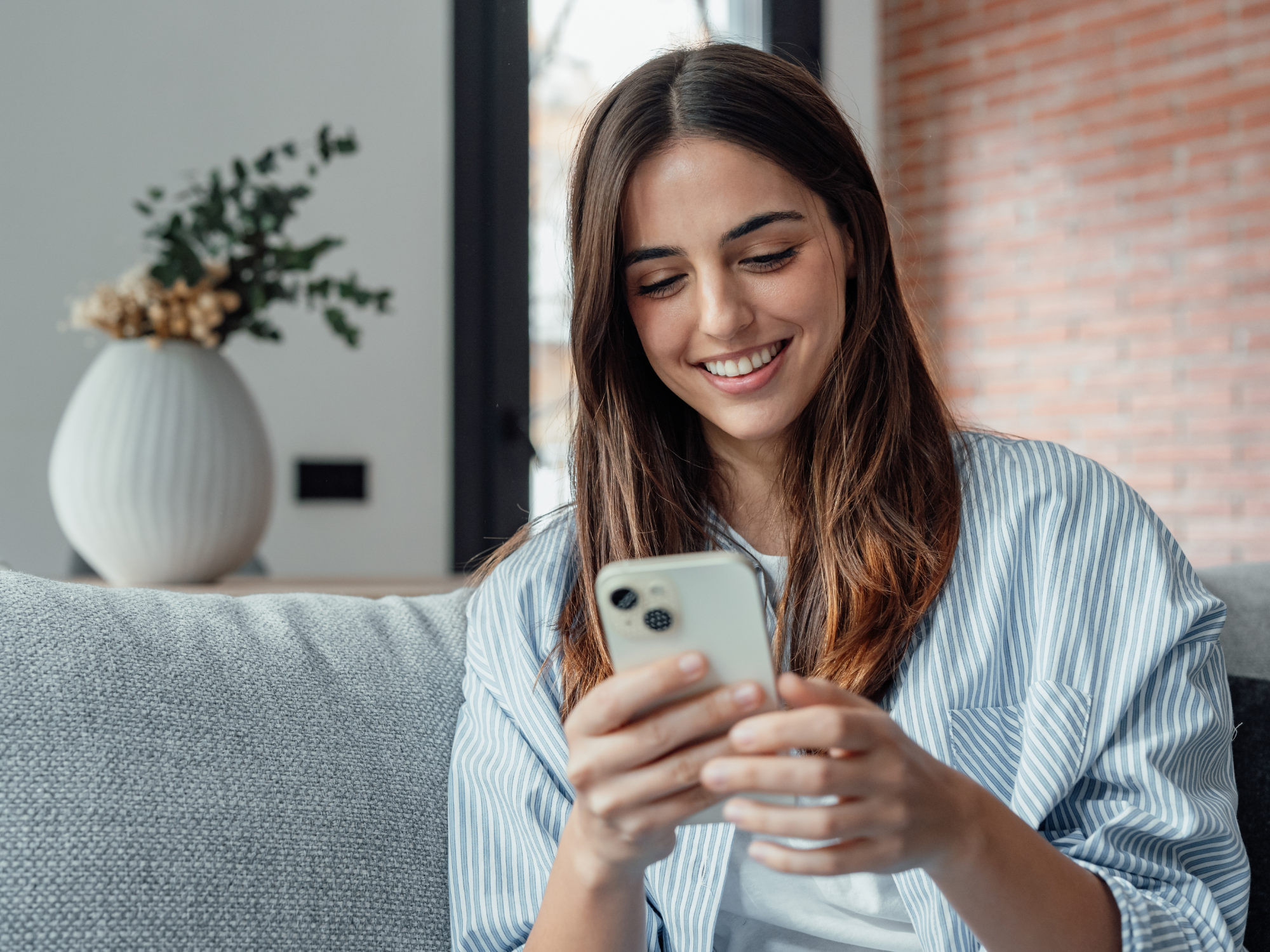 Frau sitzt mit ihrem Smartphone auf der Couch