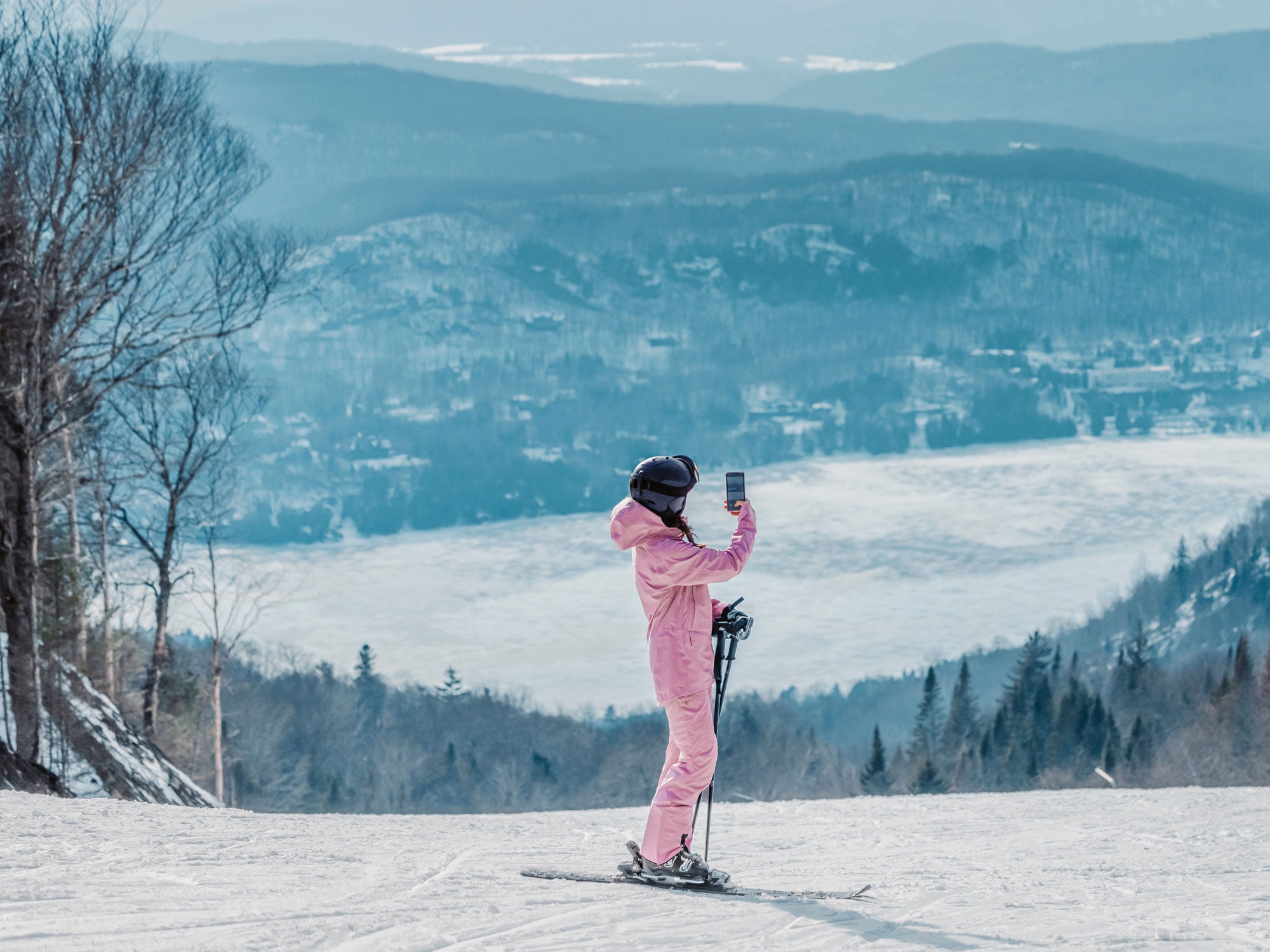 Eine Skifahrerin fotografiert das Panorama von einer Skipiste aus