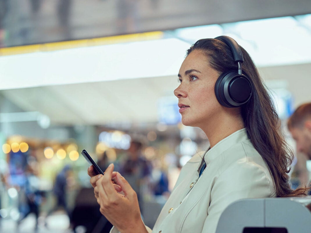 Eine Frau trägt Over-Ear-Kopfhörer an einem Flughafen