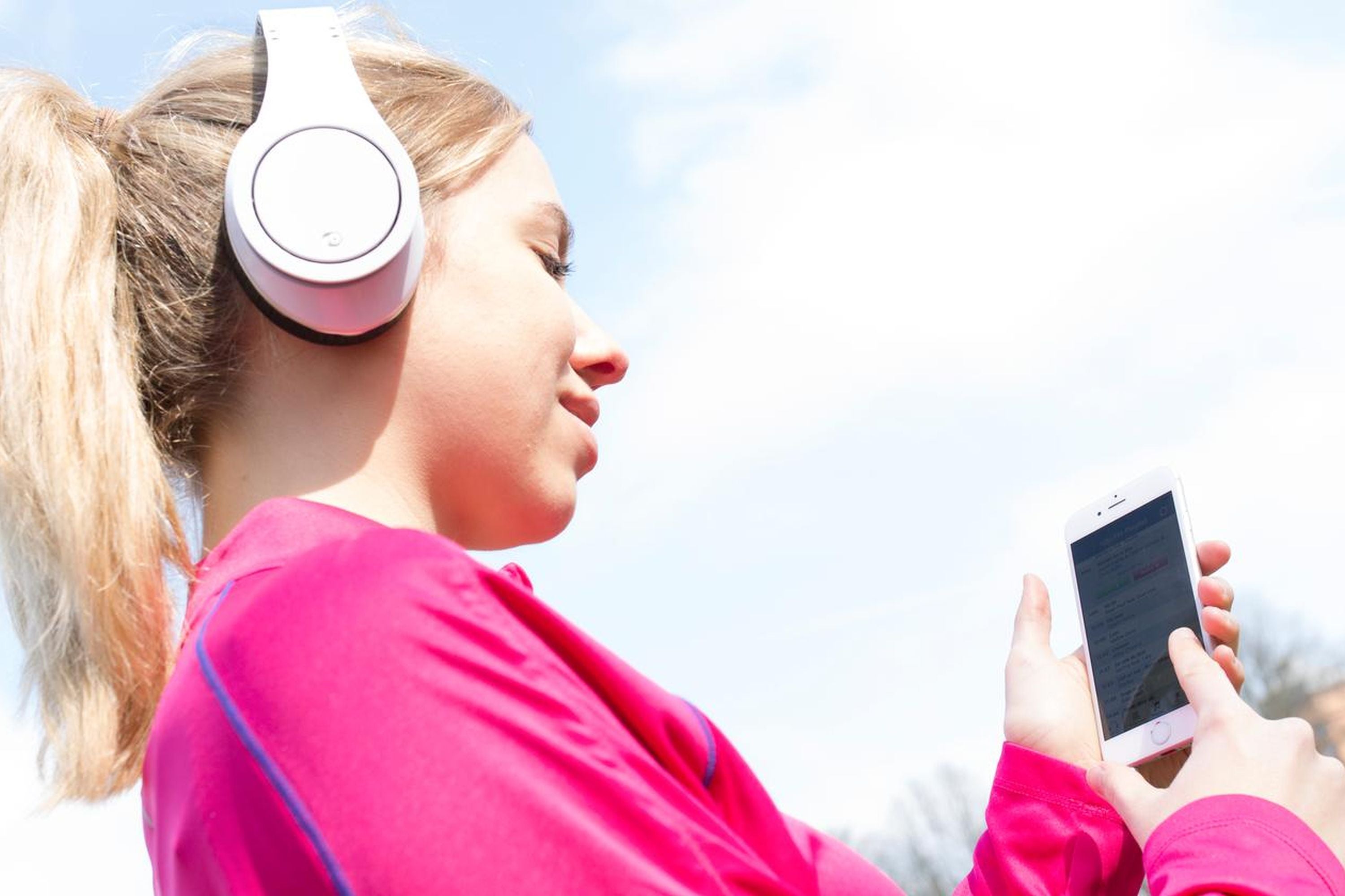 Eine Frau hört Radio mit Smartphone und Kopfhörer