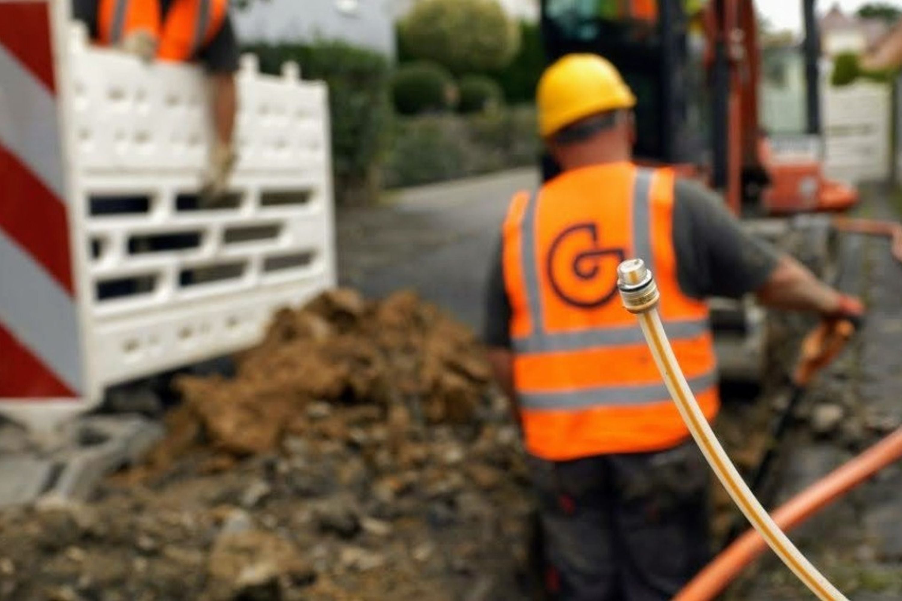 Ein Bauarbeiter steht in einem Kabelschacht. Im Vordergrund ist eine Glasfaser-Speedpipe zu sehen