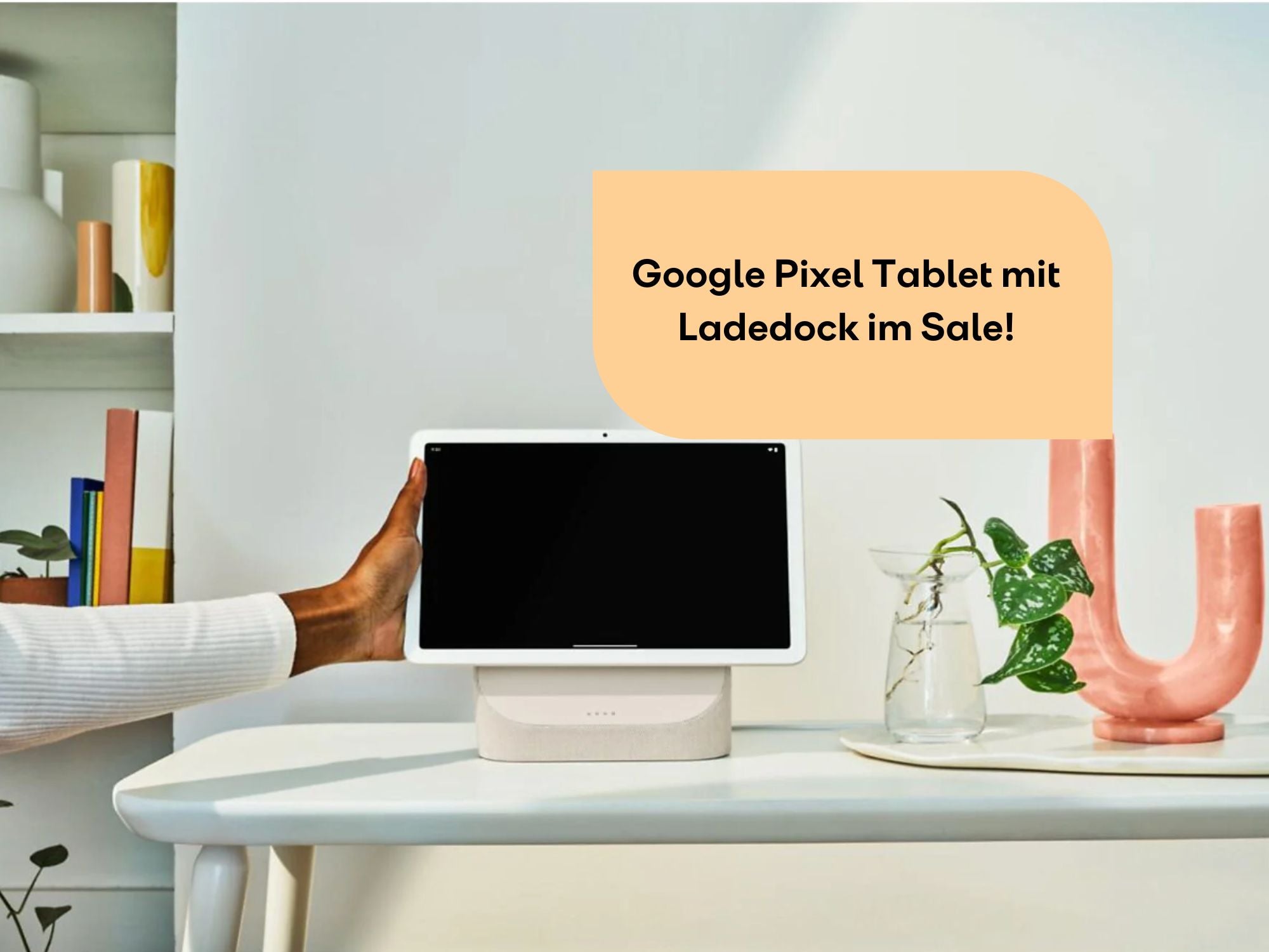 Google Pixel Tablet steht auf Ladedock. Person greift danach