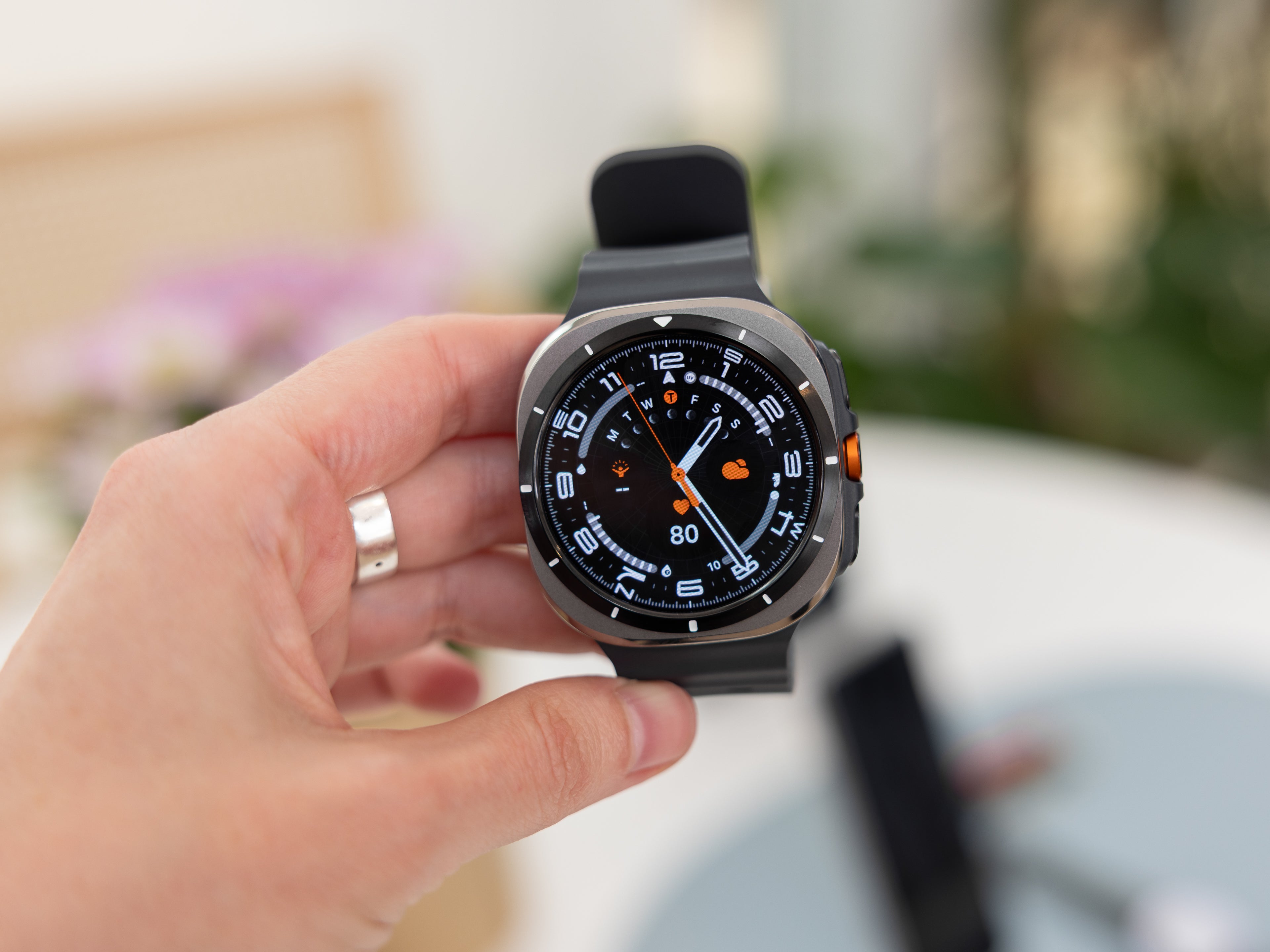 Nahaufnahme einer Hand, die die Samsung Galaxy Watch Ultra mit einem robusten Design und einem detaillierten Zifferblatt hält.