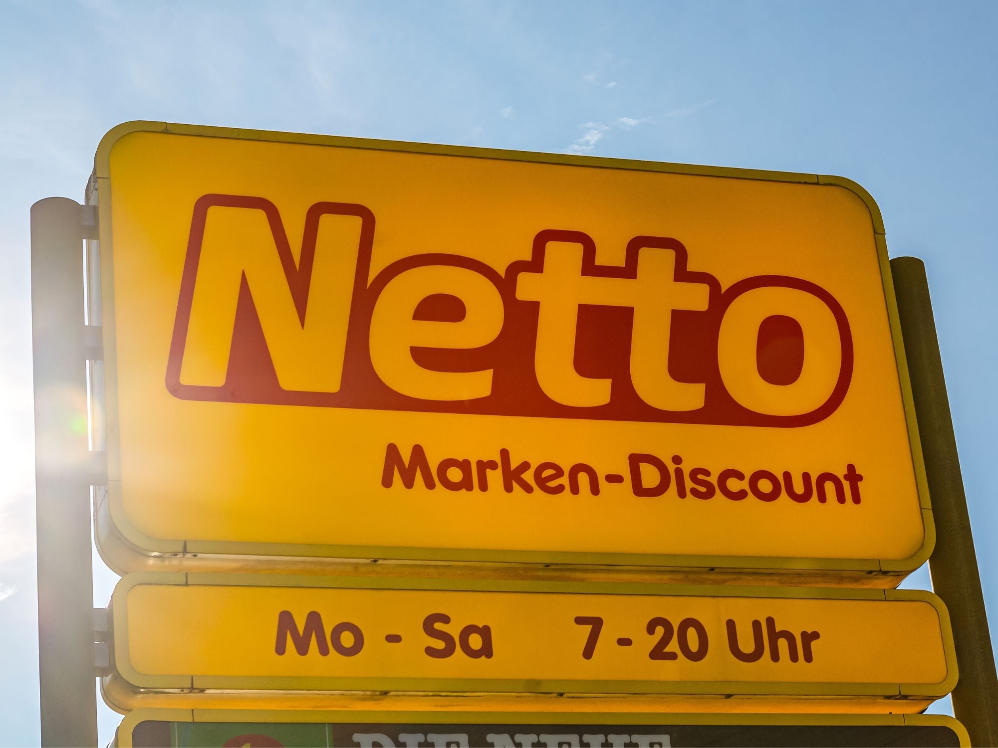 Das Netto-Logo von einem Geschäft vor einem sonnigen Himmel.