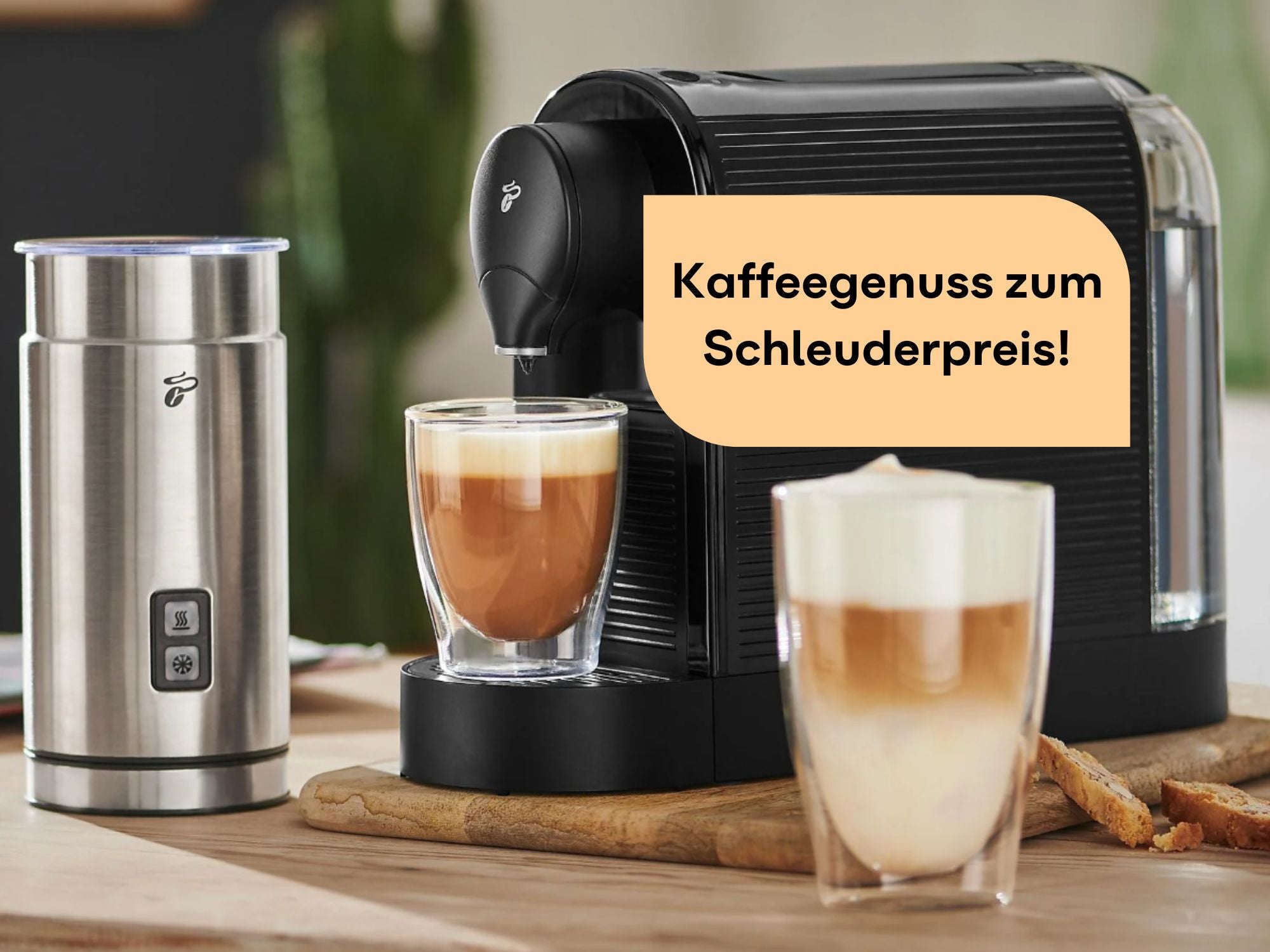 Kaffeemaschine und Milchaufschäumer stehen auf einem Tisch. Zwei Becher mit Kaffee stehen davor.