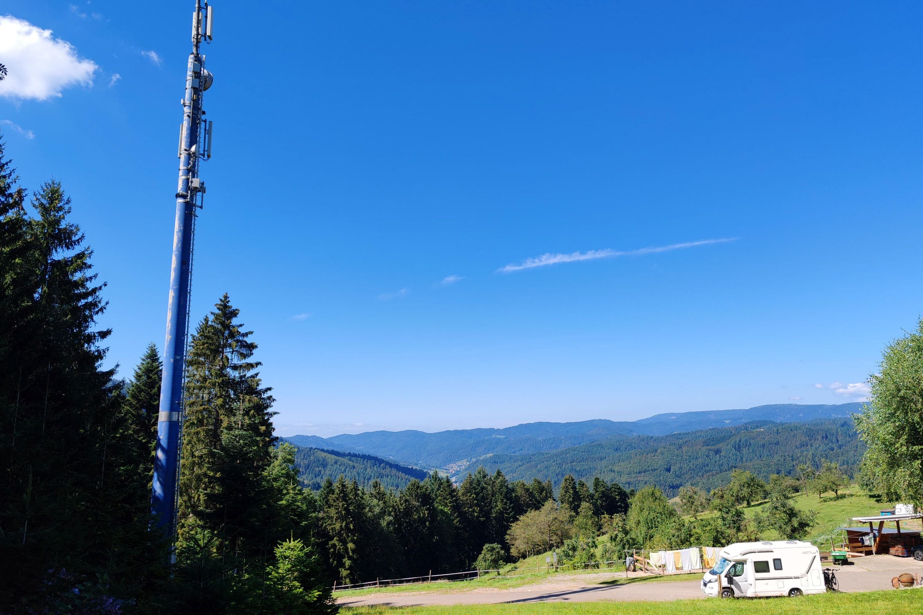 Ein Wohnmobil steht unter einer Mobilfunkantenne im Schwarzwald