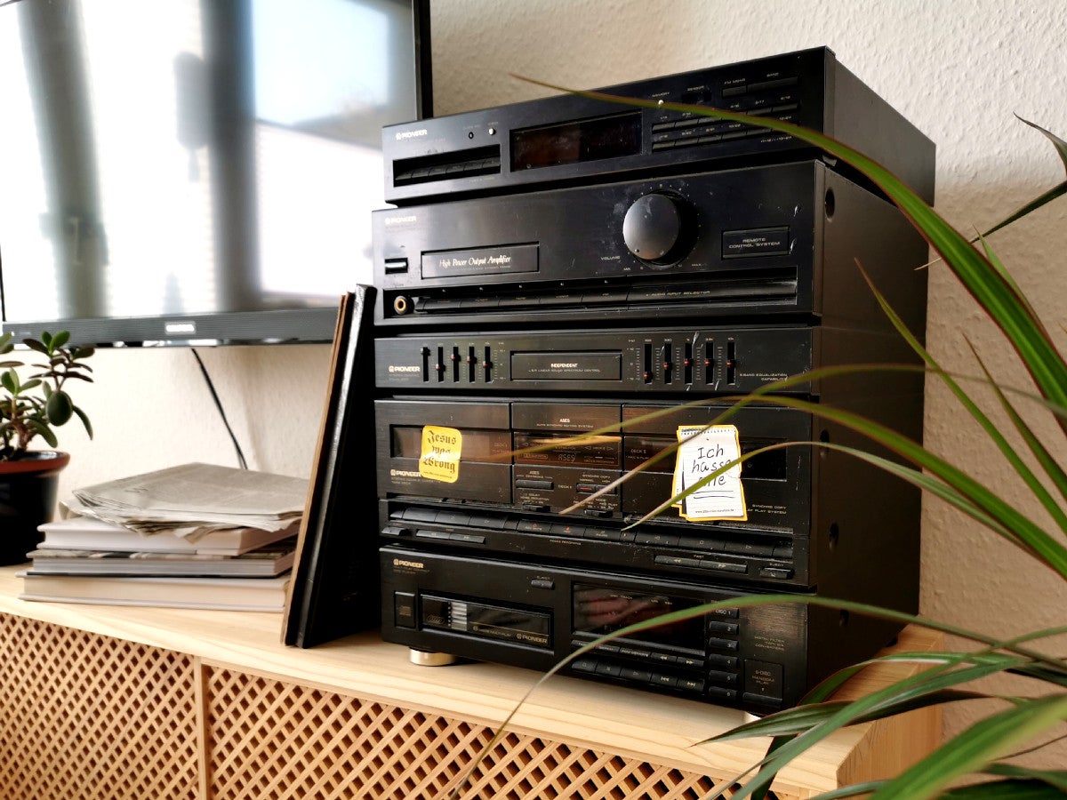 Alte Stereoanlage auf einem Holz-Sideboard neben einer Pflanze und einem TV