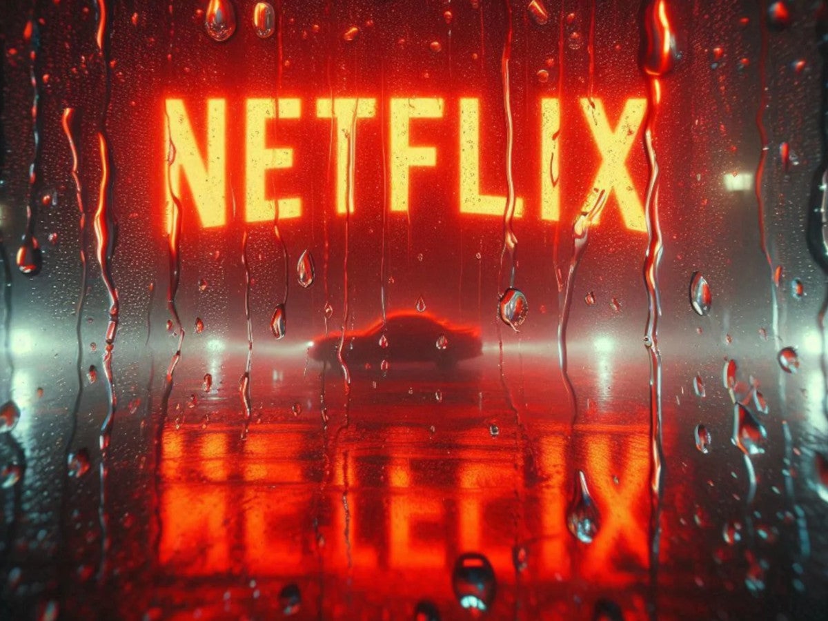 Das Netflix-Logo leuchtet hinter einem Fenster, auf dem Regentropfen laufen.