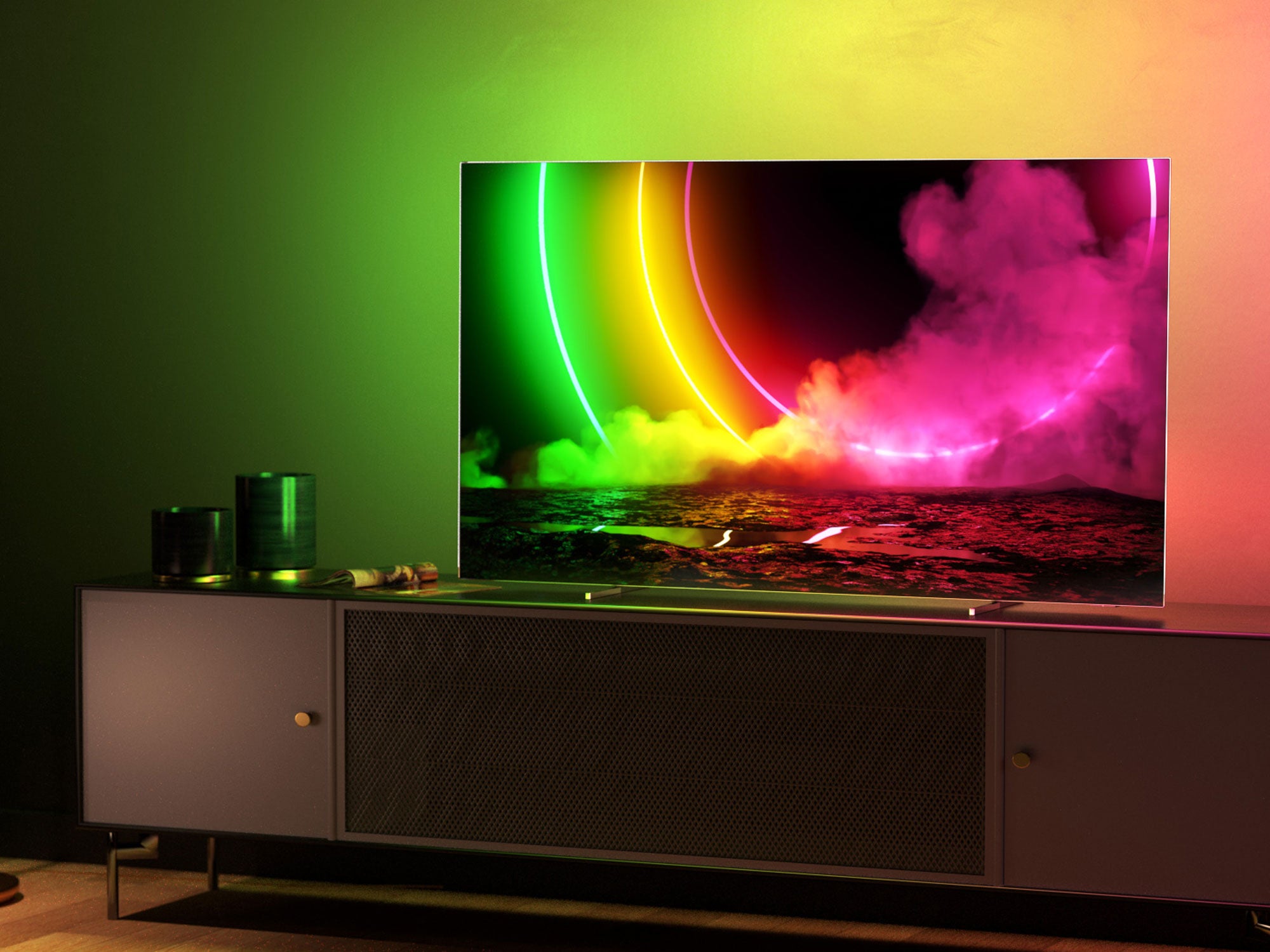 Ein Philips-Fernseher mit eingeschaltetem Ambilight-Licht steht auf einem TV-Möbel