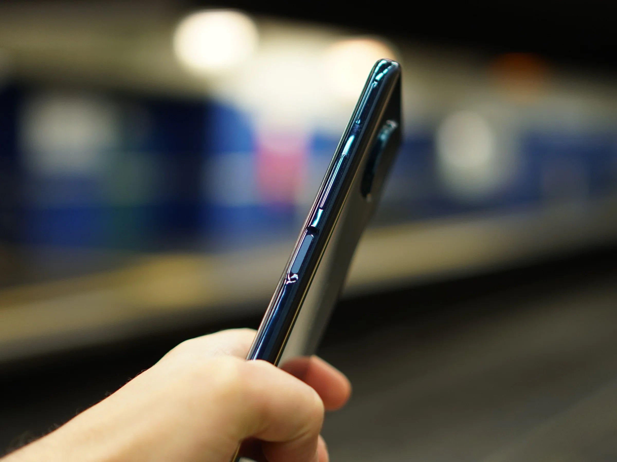 Hand hält Smartphone an einem Bahnhof mit Quishing-Fallen