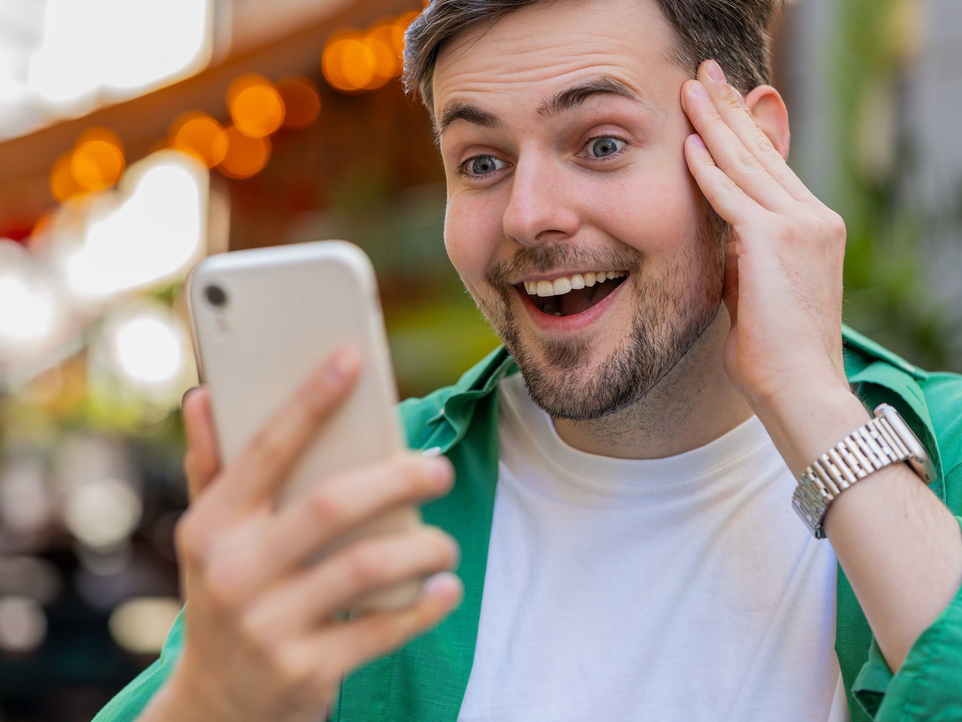 Mann mit Smartphone in der Hand freut sich.