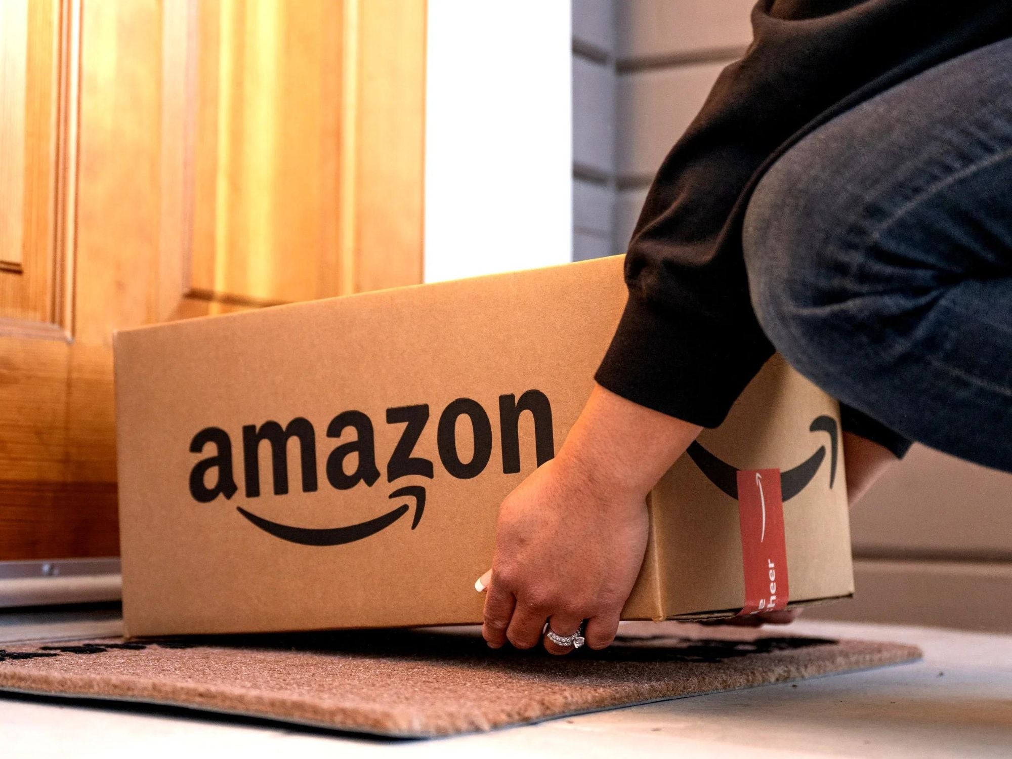 Person stellt Amazon-Paket vor einer Haustür ab