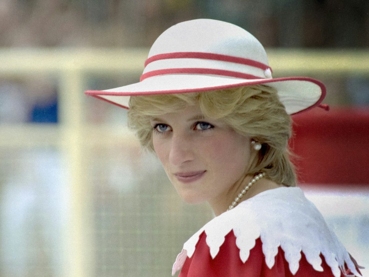 Lady Diana schaut mit weiß-rotem Hut schräg an der Kamera vorbei.