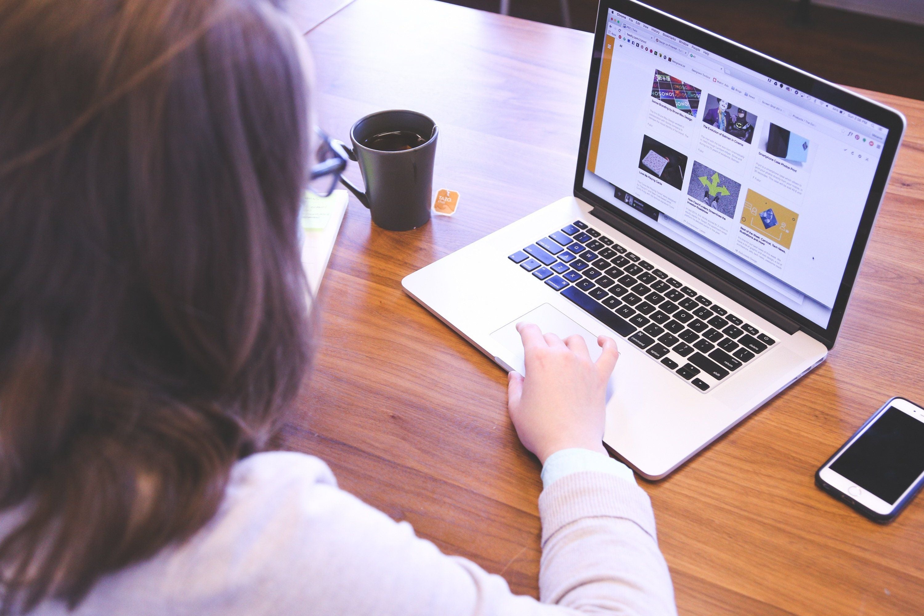 Eine Frau sitzt am Tisch an einem Laptop