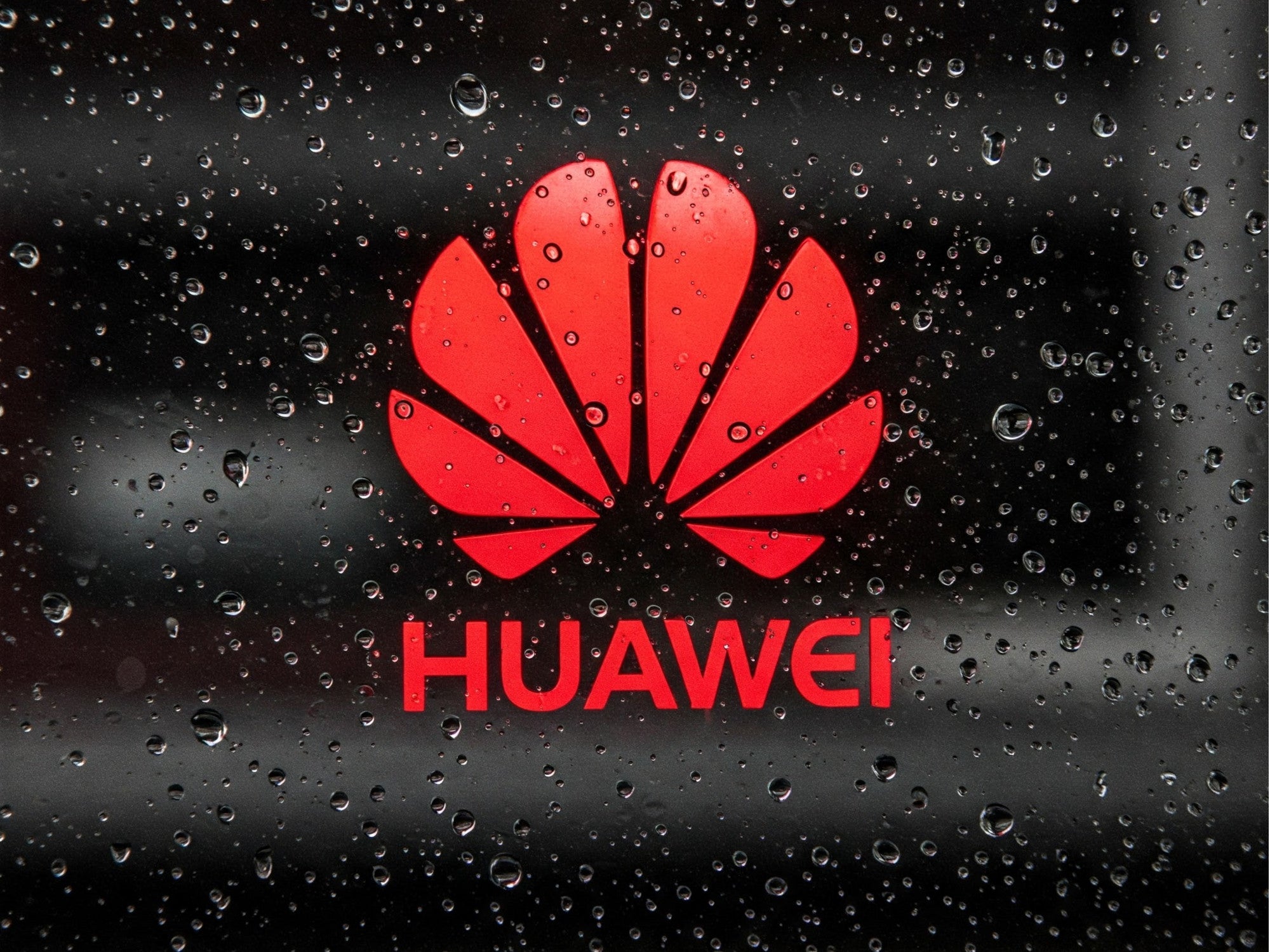 Huawei-Logo auf einer Glasscheibe mit Regentropfen.