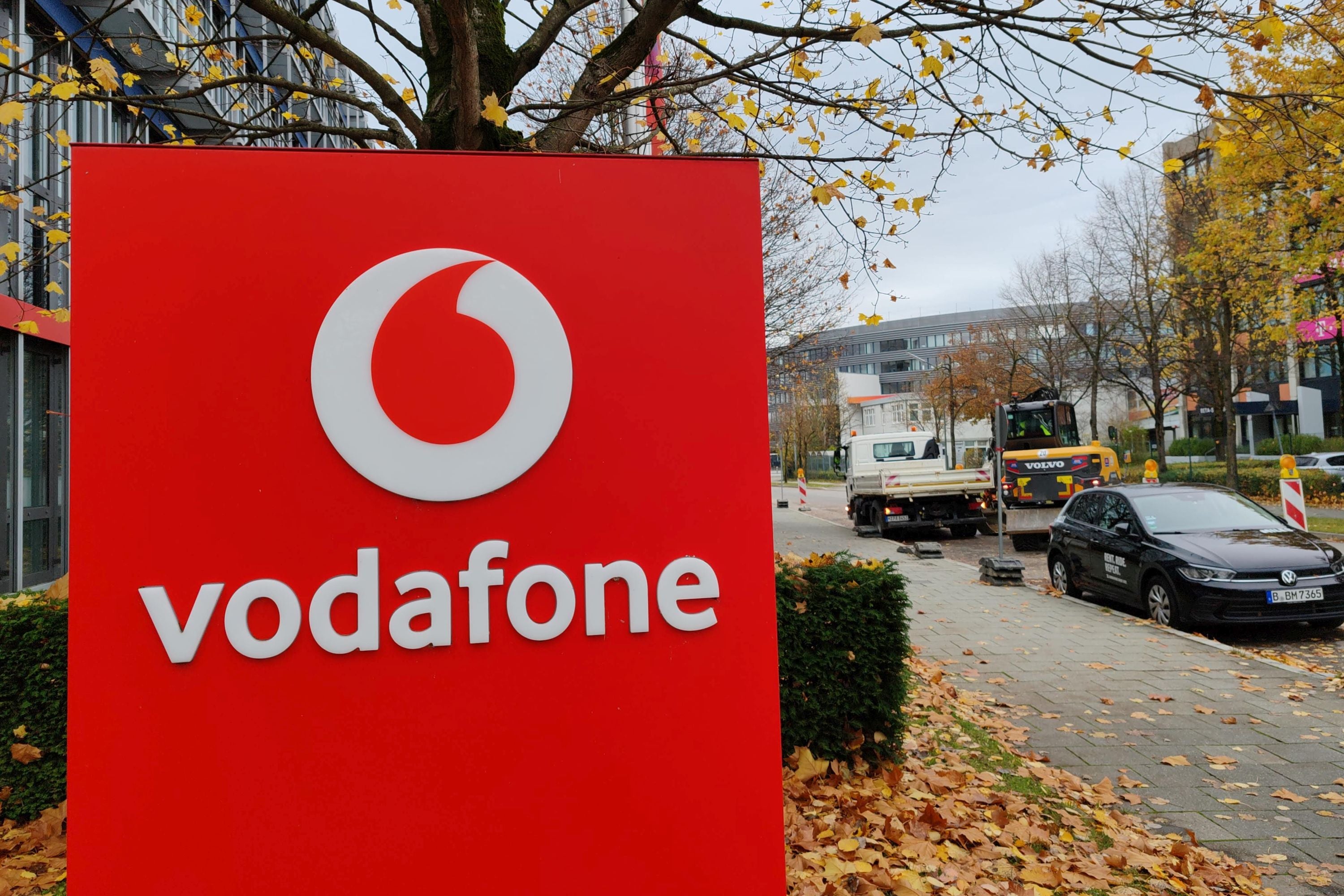 Das Logo von Vodafone auf einem Schild vor herbstlicher Kulisse