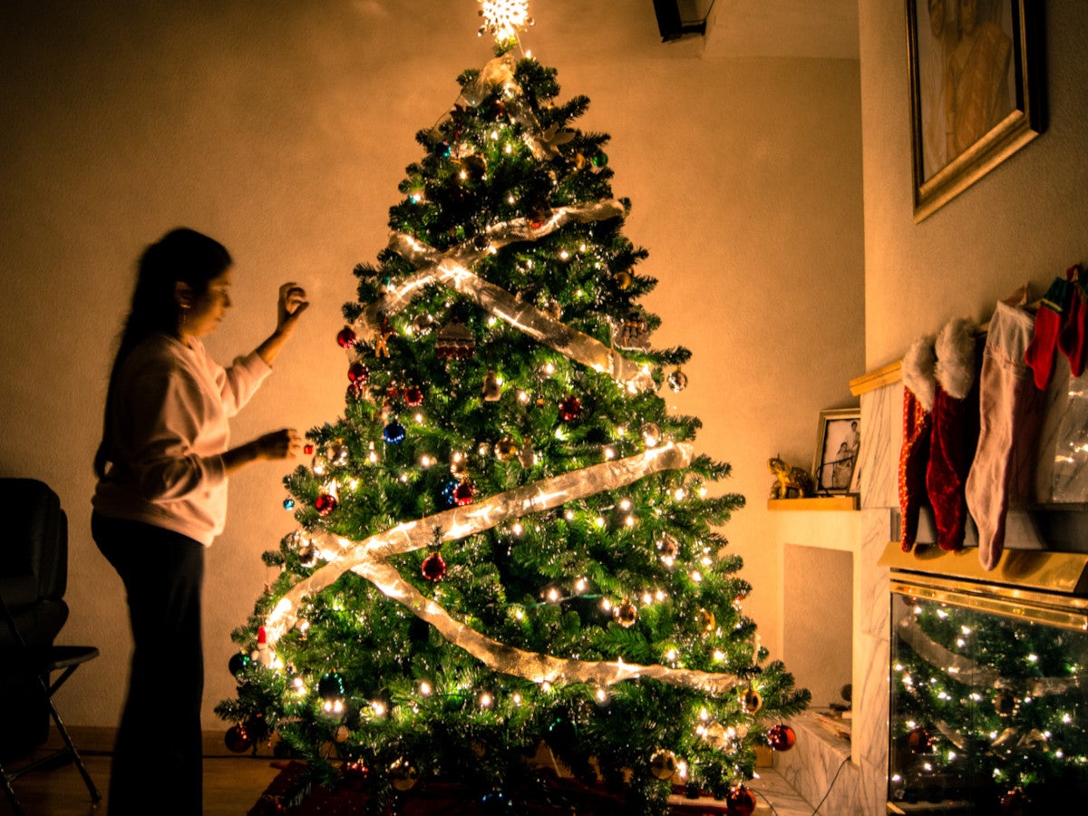 Eine Frau schmückt einen Tannenbaum.