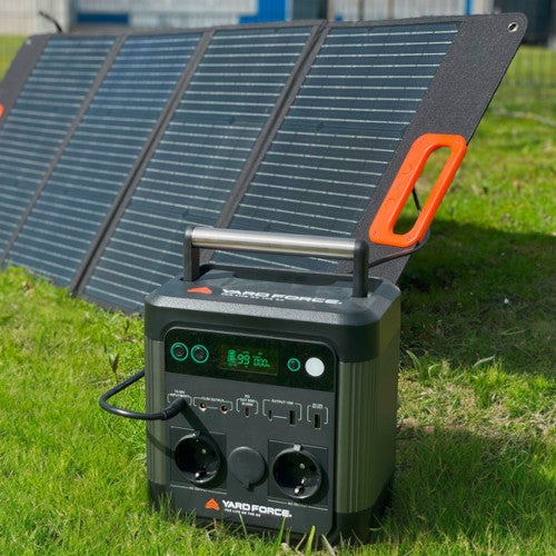 Yard Force Power Station LX PS600 + Solarpanel LX SPP10 Set auf einem Rasen.